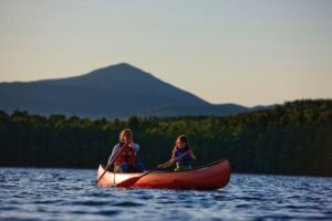 Woman and child kayaking in front of mountain